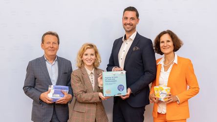 Personen stehen nebeneinander und lächeln in die Kamera, währen sie Periodenprodukte in der Hand halten.