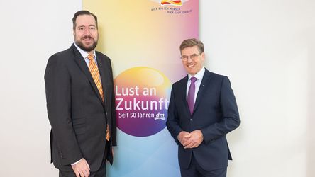 Einen gebrandeten Hintergrund, auf dem Lust an Zukunft, Seit 50 Jahren dm steht. Davor stehen Harald Bauer, Vorsitzender der dm Geschäftsführung und Thomas Köck, Geschäftsführung dm Österreich.