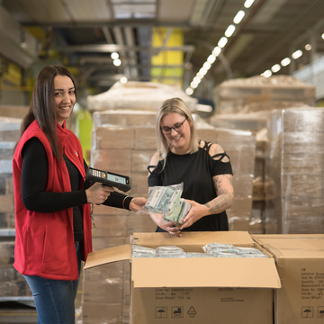 Zwei Mitarbeiterinnen stehen im Verteilzentrum und scannen Produkte aus einer Anlieferung.