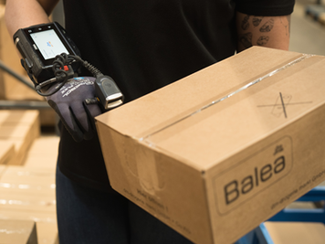 Eine Mitarbeiterin scannt eine Kiste von Balea.