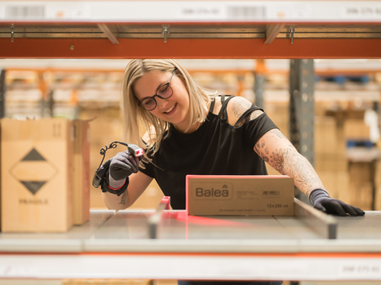 Mitarbeiterin scannt eine Kiste von Balea.