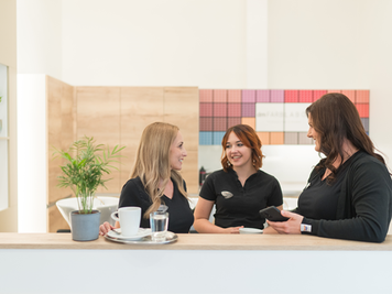 Drei Friseurmitarbeiterinnen machen eine Kaffeepause im dm friseurstudio.