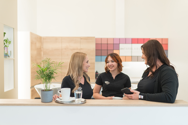 Drei Friseurmitarbeiterinnen machen eine Kaffeepause im dm friseurstudio.