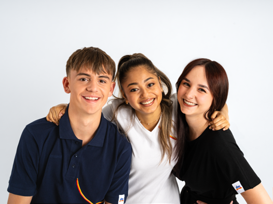 Drei Lehrlinge stehen zusammen und lachen in die Kamera.