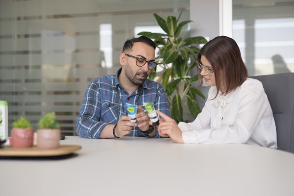 Ein Mitarbeiter und eine Mitarbeiterin sitzen am Besprechungstisch und besprechen dm Produkte.