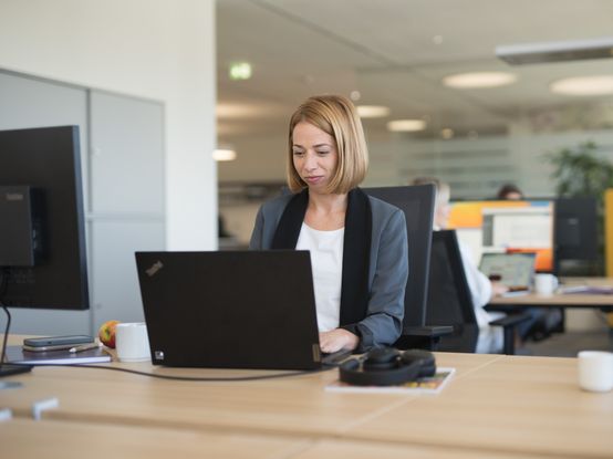 Eine Person sitzt am Laptop und tippt konzentriert auf der Tastatur.